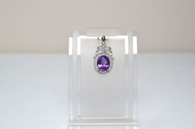 a close up of a purple and white diamond pendant on a clear display case