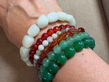 a woman ' s hand holding a bunch of bracelets on a table