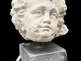 marble head of a woman with curly hair on top of a stone block