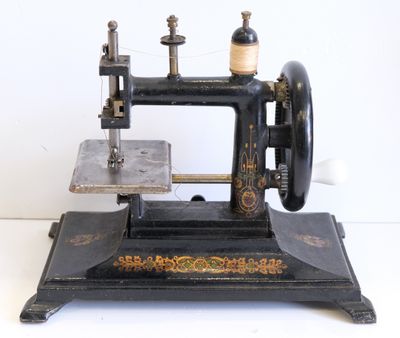 une machine à coudre noire et dorée posée sur une surface blanche