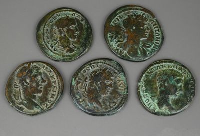 quatre pièces de monnaie romaines anciennes, avec une tête romaine d'un côté et une autre tête romaine de l'autre