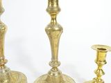 three brass candlesticks sitting next to each other on a white surface