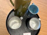 two cups and a pitcher on a tray on a table