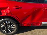 a close up of a red car that has a dent in it