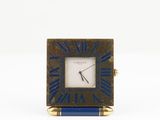 une image représentant une petite horloge carrée avec un cadre bleu et doré
