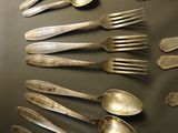 a lot of silver spoons and forks on the table