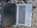 an open laptop computer sitting on the ground next to a cell phone