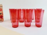 six red glasses and a can of soda on a table