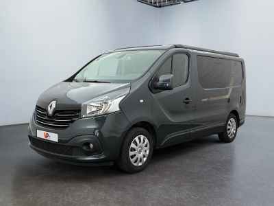 La camionnette grise est garée dans une pièce blanche au sol noir.