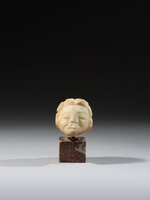 une tête de femme sculptée dans l'ivoire, posée sur un bloc de marbre