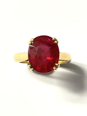a close up of a red stone ring on a white surface