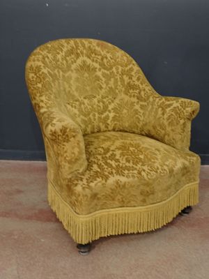 une chaise jaune ornée de franges, posée devant un mur gris