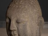 statue of a buddha head on a table in front of a black wall