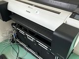 a large black and white printer sitting on the floor next to a laptop