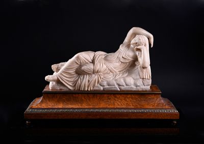 marble statue of a woman reclining on a bed on a black background