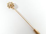 une image représentant une broche en or surmontée d'une fleur