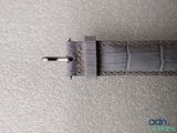 the watch strap is made of grey alligator leather and has a silver buckle