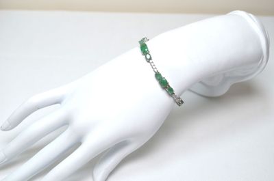 a white mannequin hand with a green bracelet on it
