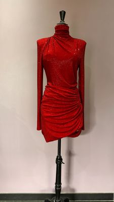 une robe rouge posée sur un mannequin devant un mur blanc