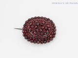 un gros plan d'une broche en perles rouges posée sur une surface blanche
