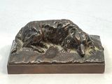 statue représentant un chien couché sur un socle en bois