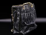 a black chanel bag with gold chains on a black background