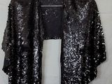 a black sequinned jacket hanging on a hanger on a wall