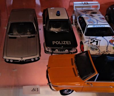 Plusieurs petites voitures sont exposées dans une vitrine.