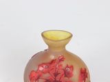 a small vase with red flowers on it on a white surface