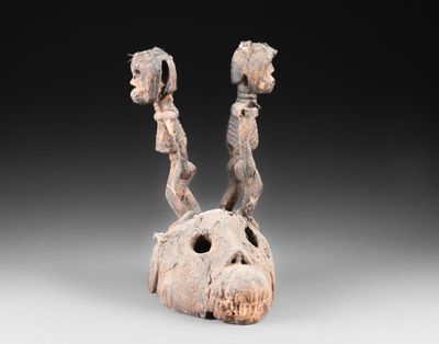 une image représentant une sculpture en bois représentant deux personnes sur un crâne