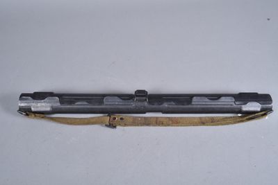 un vieux pistolet muni d'une sangle, posé sur une surface blanche