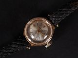 an old gold watch with a black leather strap on a black surface