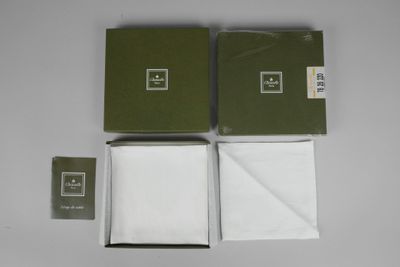 deux boîtes de serviettes blanches posées sur une table blanche