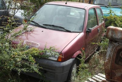 a red car that is sitting in the weeds