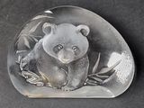 a glass bear sitting on top of a rock on a table