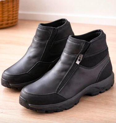 une paire de bottes noires posées sur un parquet, avec un panier en arrière-plan