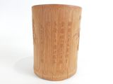 une tasse en bambou posée sur une surface blanche