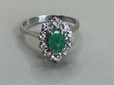 a picture of a ring with a green stone surrounded by white diamonds