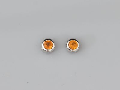 une paire de boucles d'oreilles en topaze orange posées sur une surface blanche