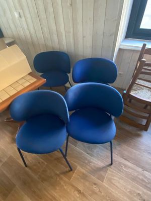 quatre chaises bleues placées dans une pièce, à côté d'une table en bois
