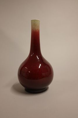 un vase rouge surmonté d'un couvercle blanc, posé sur une table