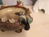 a ceramic bird sitting on top of a bowl on a table