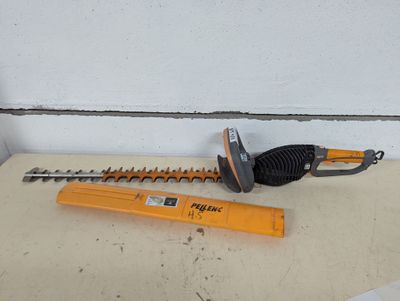 une photo d'une taille-haie filaire et d'une règle posées sur une table
