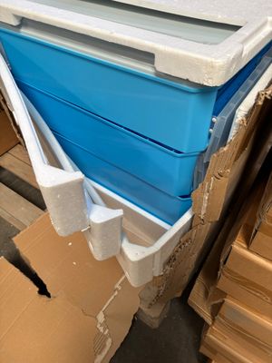 une glacière bleue et blanche posée sur une palette à côté de cartons