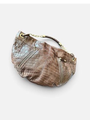 le sac à main en cuir de crocodile marron est posé sur une surface blanche