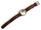 a close up of a watch on a white surface with a brown strap