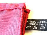 pink shirt with a black label on it sitting on top of a white table