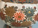 a white vase with colorful flowers on it on a table