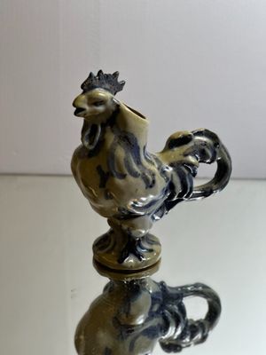 une figurine représentant un coq posée sur une table en verre