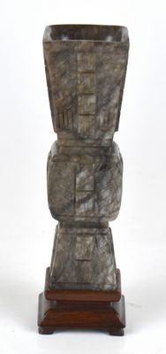 un vase en pierre posé sur un socle en bois, sur fond blanc